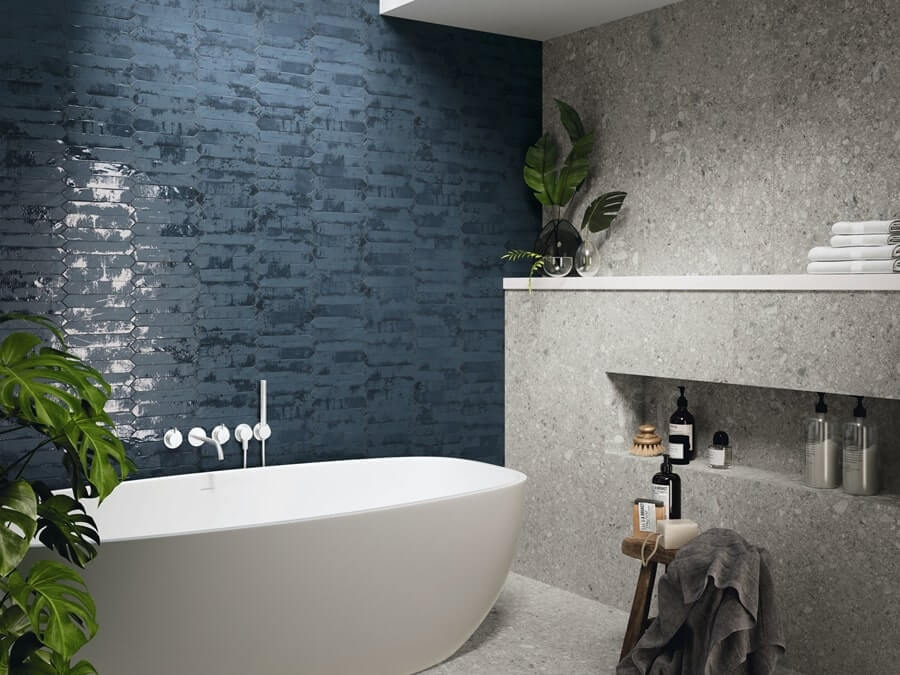 Granatowe płytki w łazience, niebieska cegiełka, imitacja betonu, szare kafelki, biała wanna, kwiaty w łazience